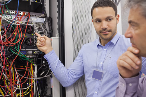 Two technicians looking at wiring of servers in data center Two technicians looking at wiring of servers in data center